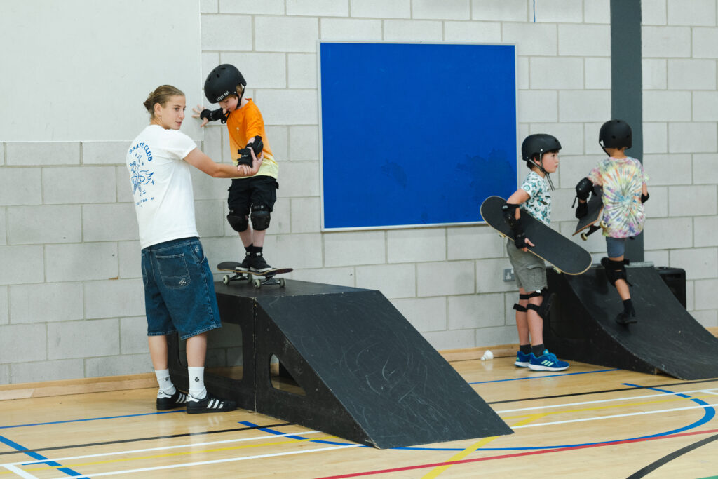 'The Skate Club' coach Kaz helping a child skateboard down a ramp